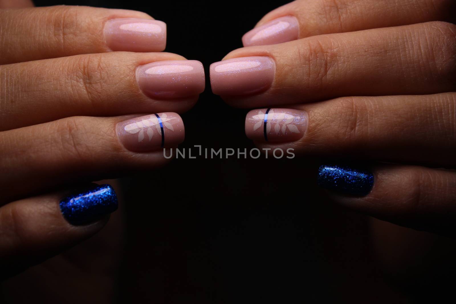 Closeup of hands of a young woman with dark red manicure on nails against white background