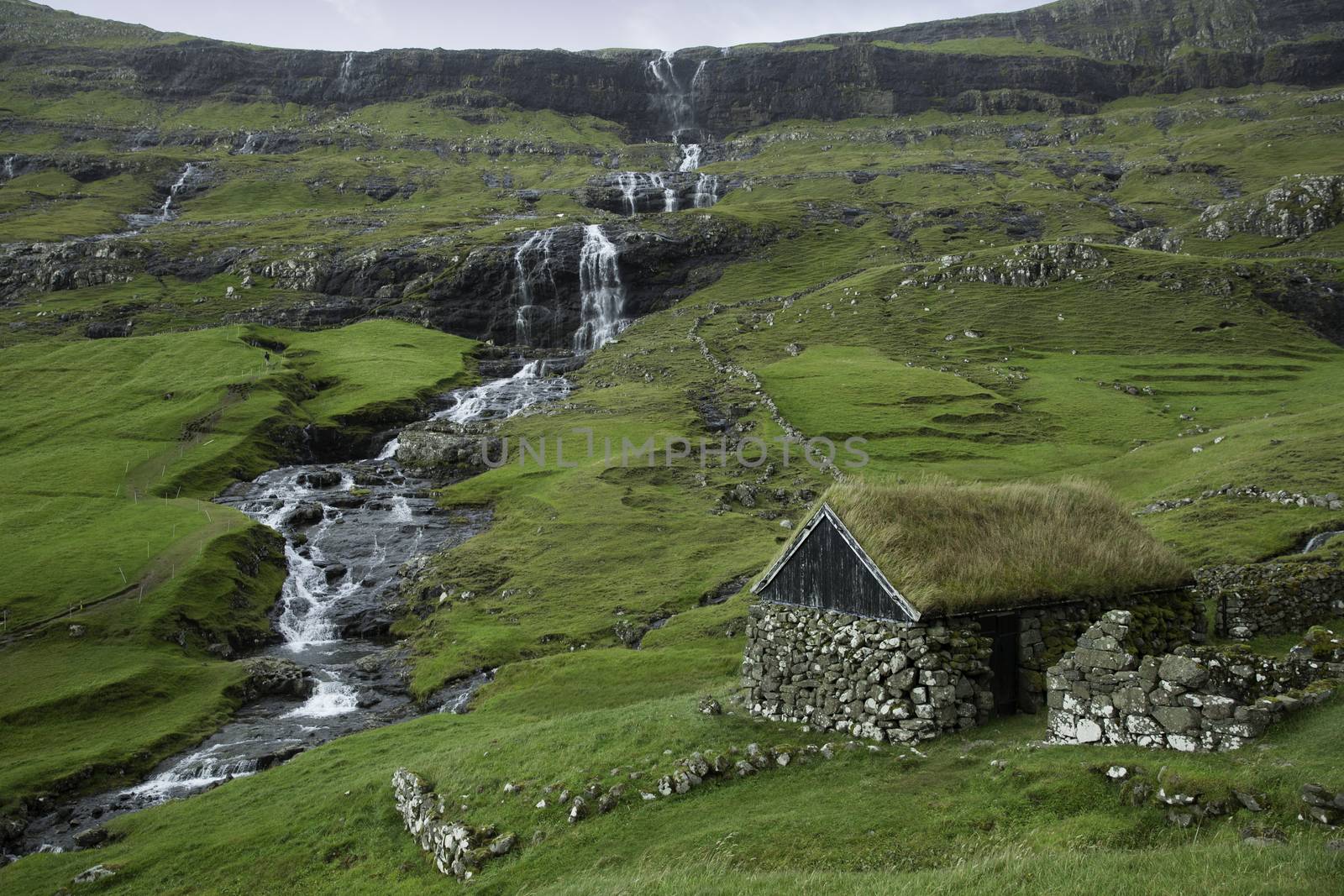 Saksun, Faroe Island - 18 September: Landscape showing a typical hut with grass roof and waterfall