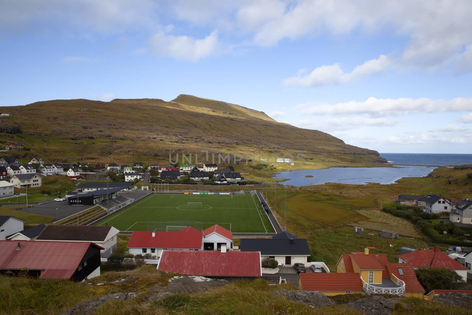 Scenic panoramic landscape of a picturesque village of Eidi with football stadium and traditional houses on the Faroe Islands
