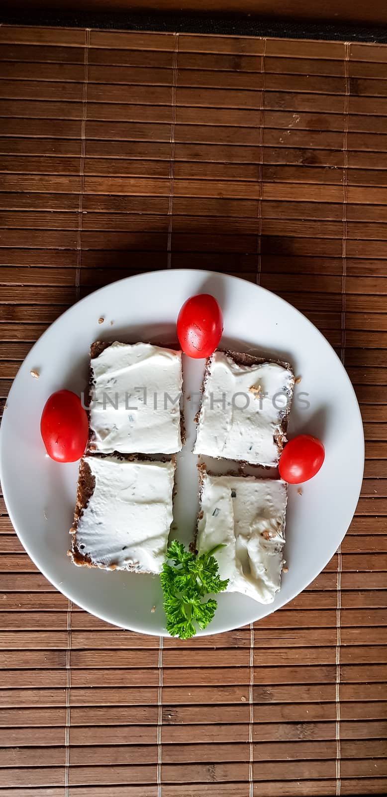 Homemade wholemeal brown bread with cottage cheese and parsley on brown bamboo base.