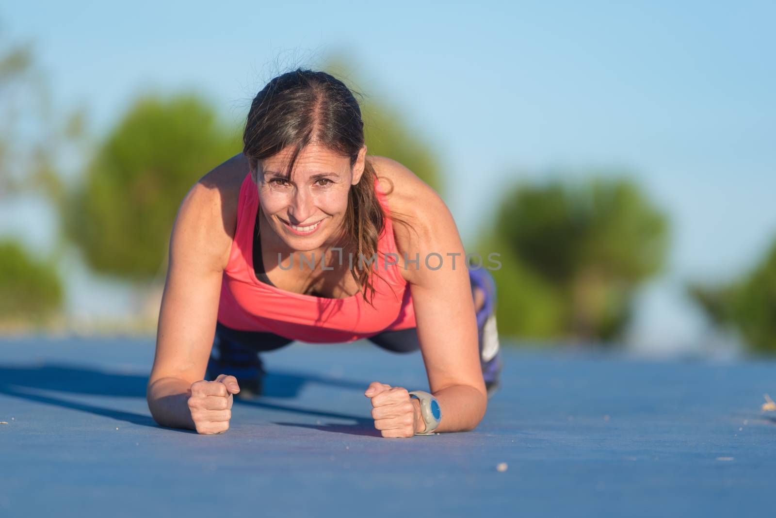 Fitness woman doing push-ups during outdoor cross training workout by HERRAEZ