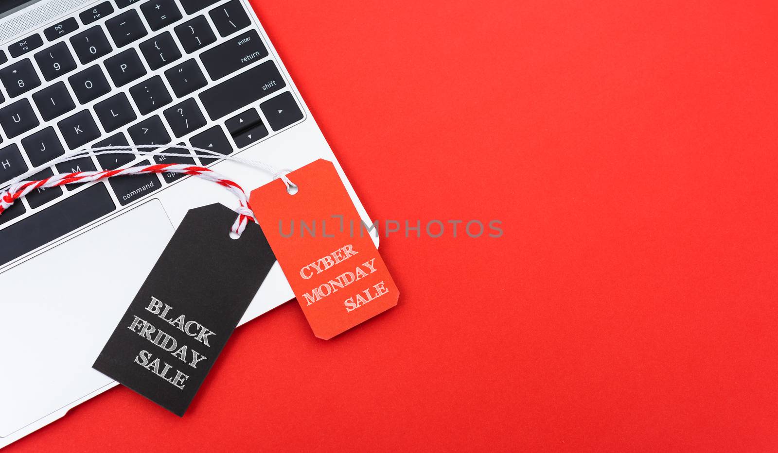 Internet online shopping marketing, top view of workspace with Black Friday text black tag and Cyber Monday text red tag near laptop computer on red background