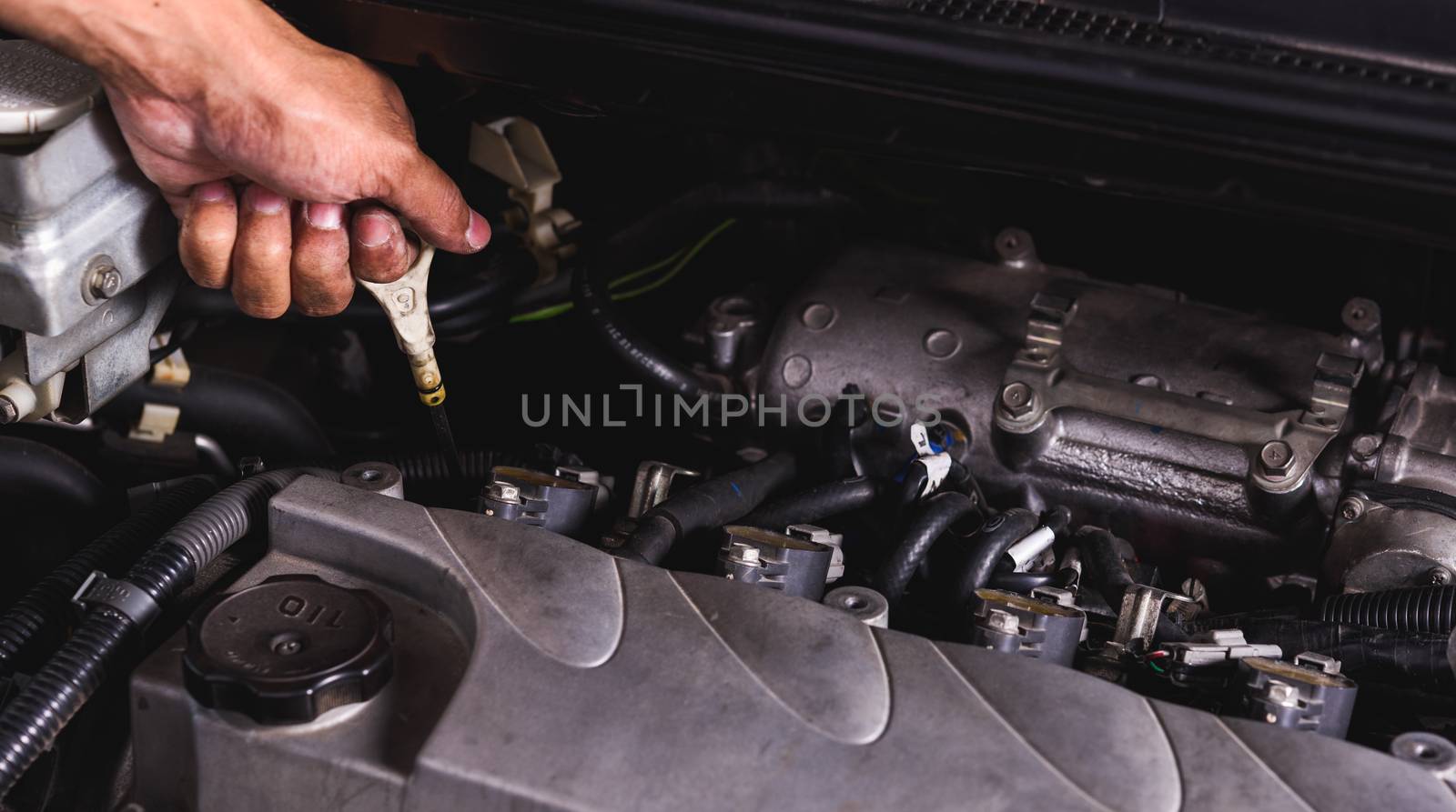 Hand of Mechanic technician service check level motor oil engine by Sorapop