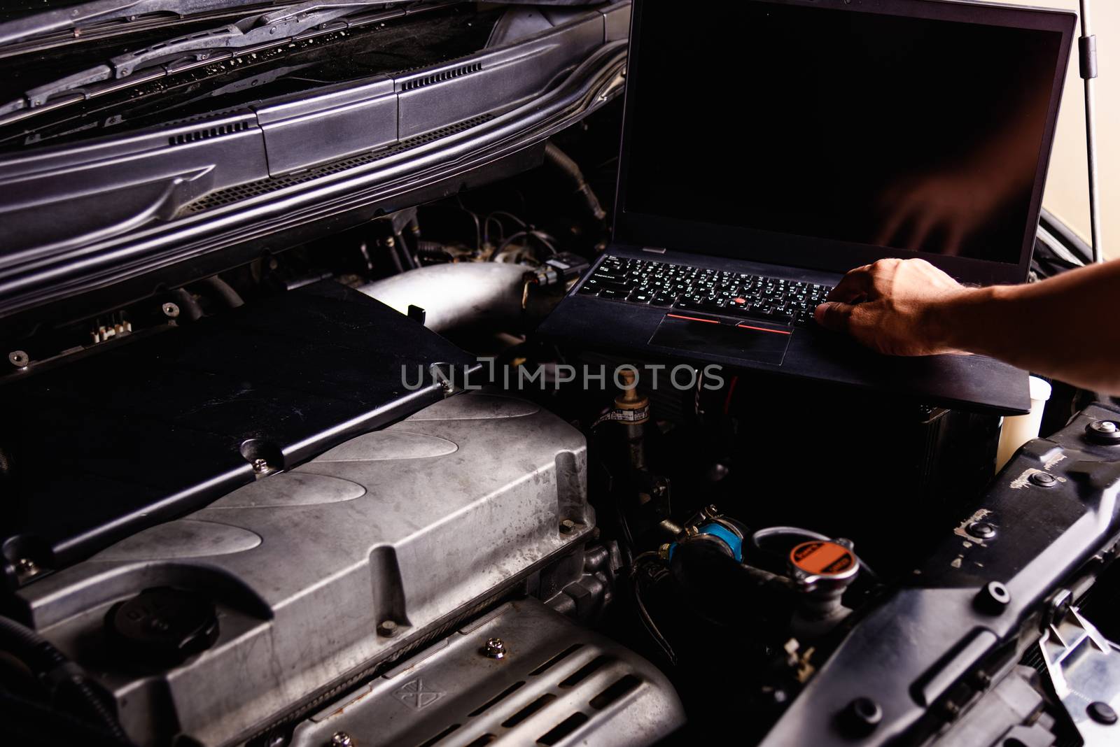 Laptop computer on car mechanic engine for service by Sorapop