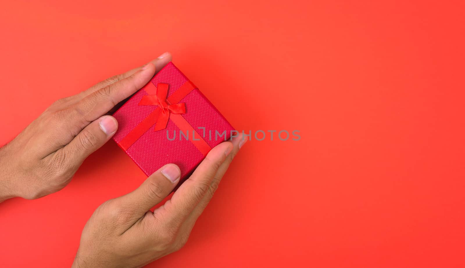 Valentine's Day Concept, Top view Flat lay, Hand holding gift box on red background with copy space for your text