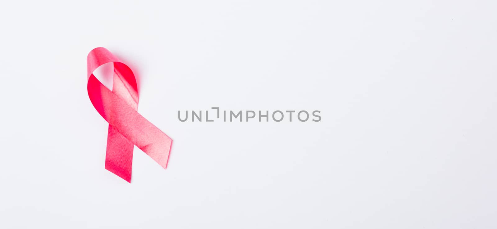 Breast cancer month concept, flat lay top view, pink ribbon on white background with copy space for your text