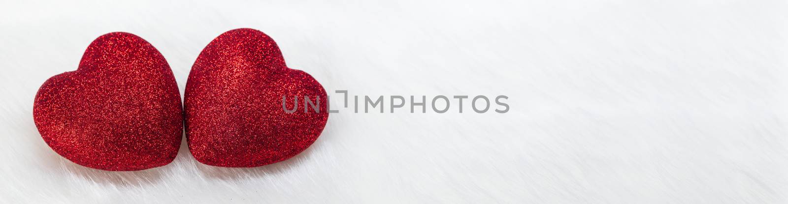 Two glitter hearts on white fur background with copy space for text