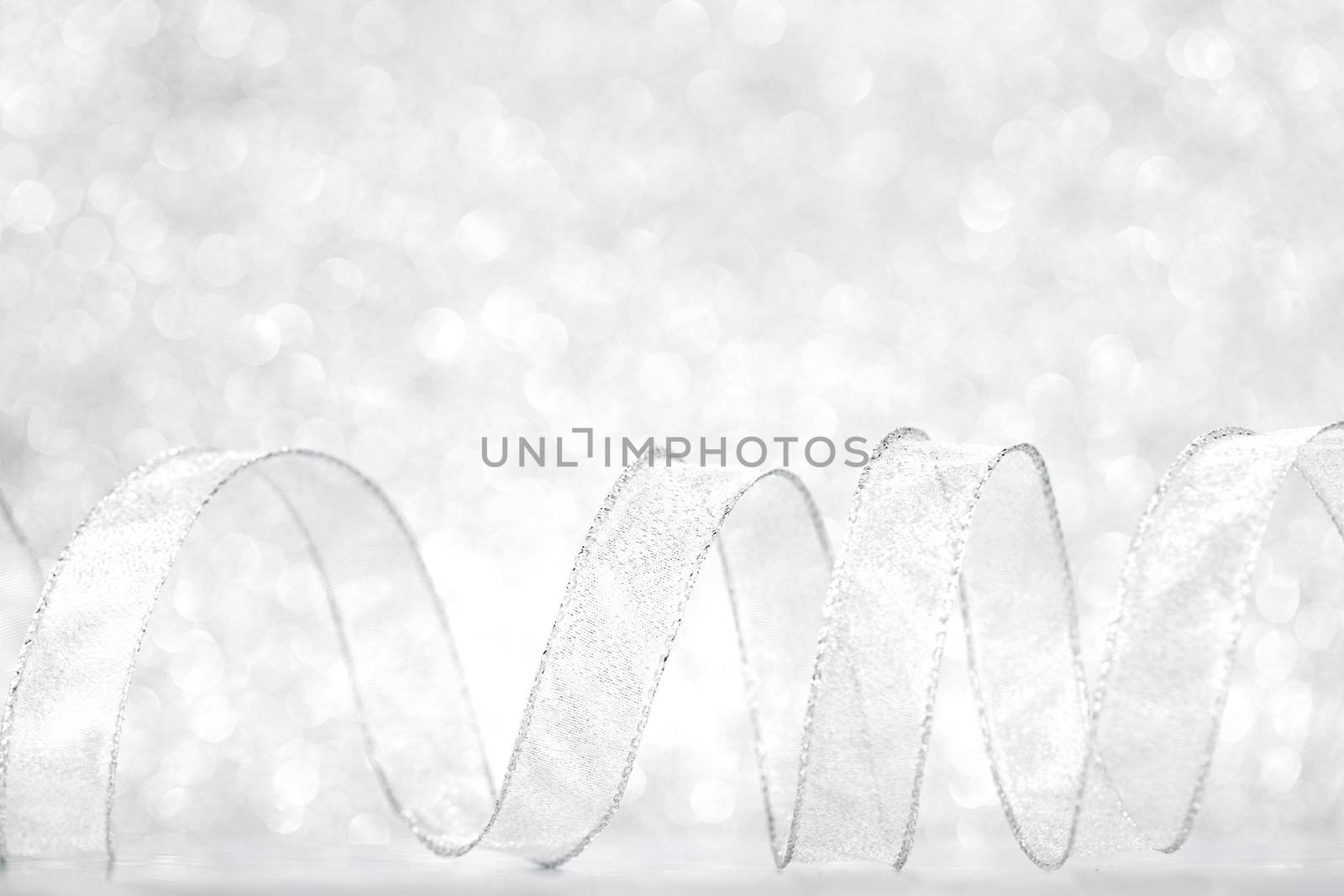 Shiny silver gift ribbon on bokeh background close-up