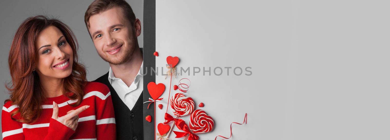 Happy young couple with heart shaped red decoration on white banner background with copy space for text. Valentine's day celebration
