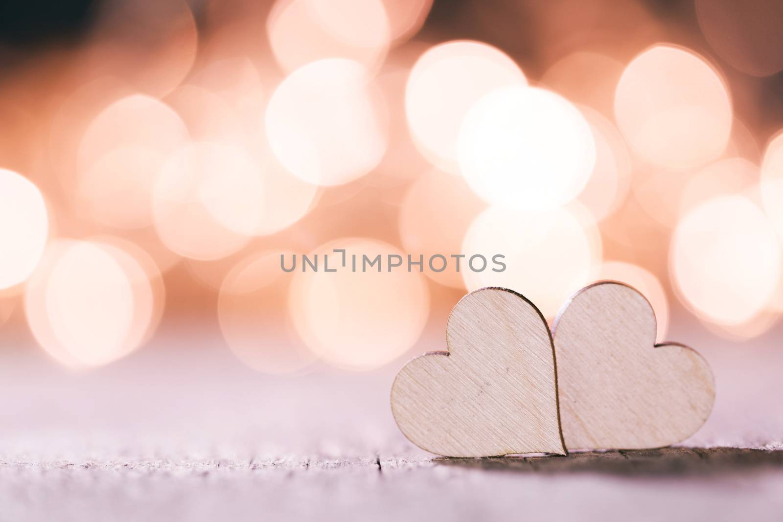 Two handmade wooden hearts on beautiful pink bokeh background. Vintage style. Love Valentine's Day concept.