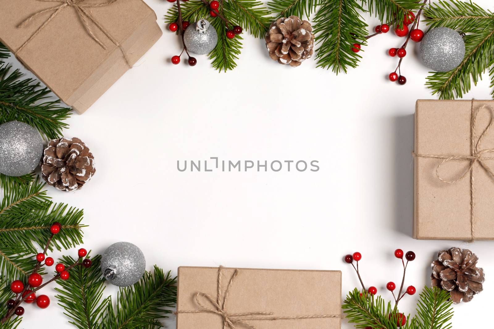 Christmas tree branch with snow , pine cones, red berries and gift boxes on white background with copy space