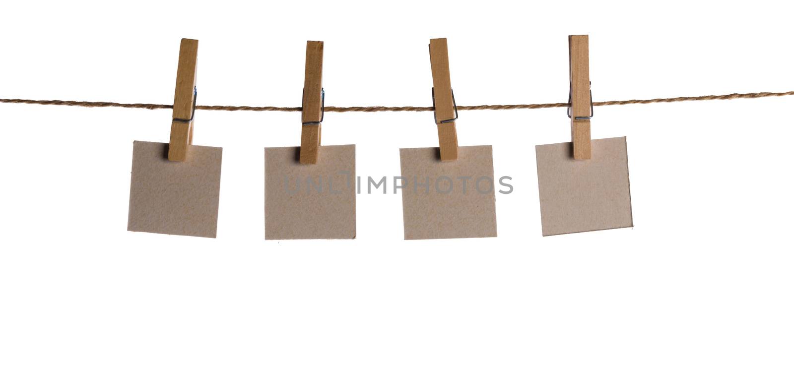 Set of four blank paper notes held on a string with clothespins isolated on white background