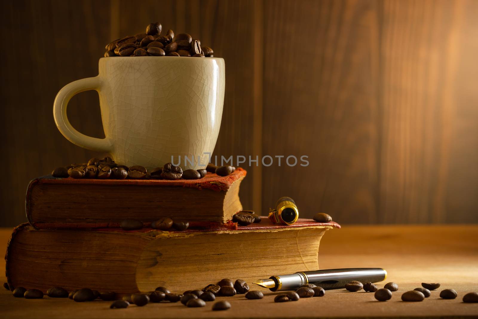 Coffee bean in the white cup and vintage book stacking on wooden table in morning light.