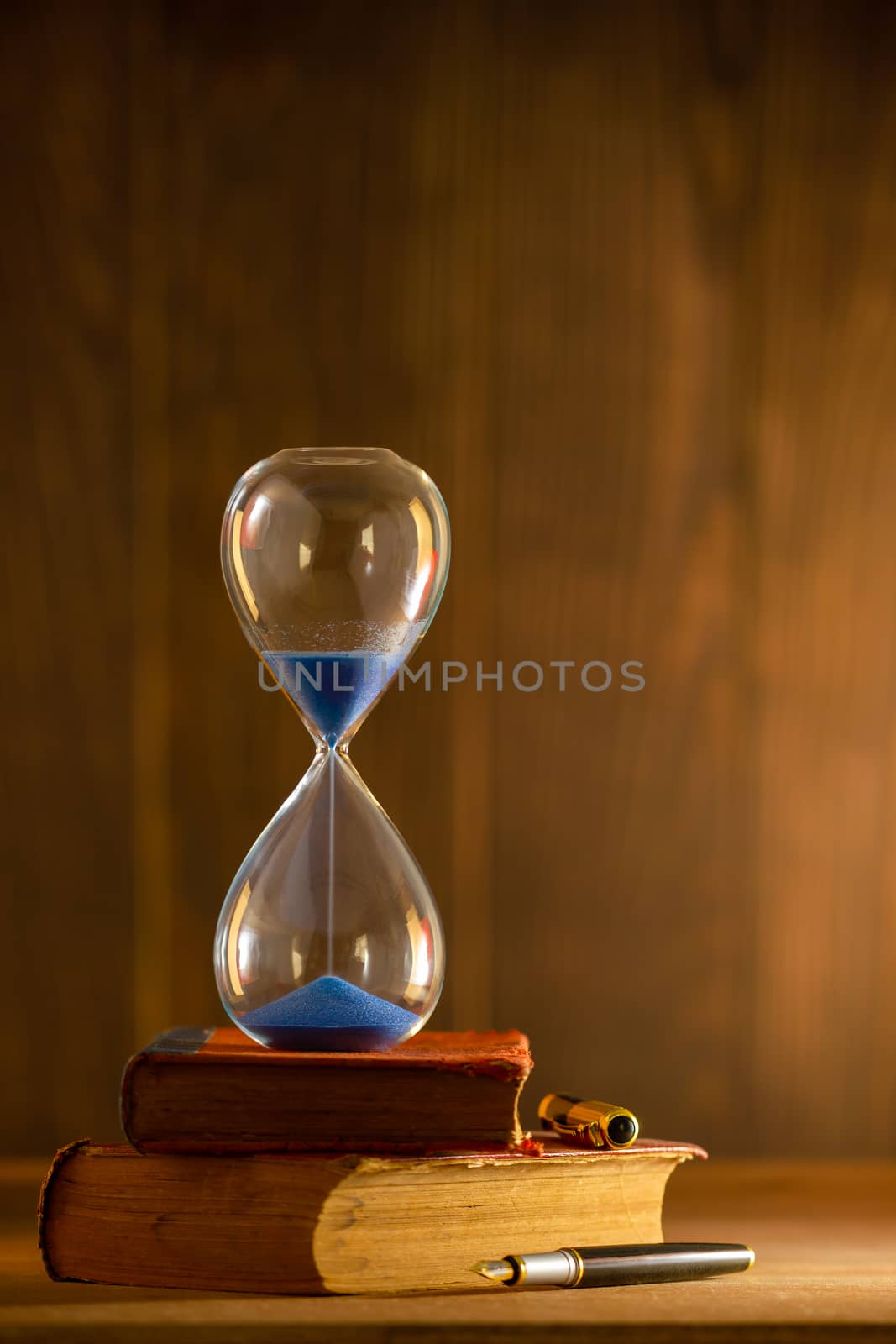 Hourglass on old book in morning light. Time of reading a book.