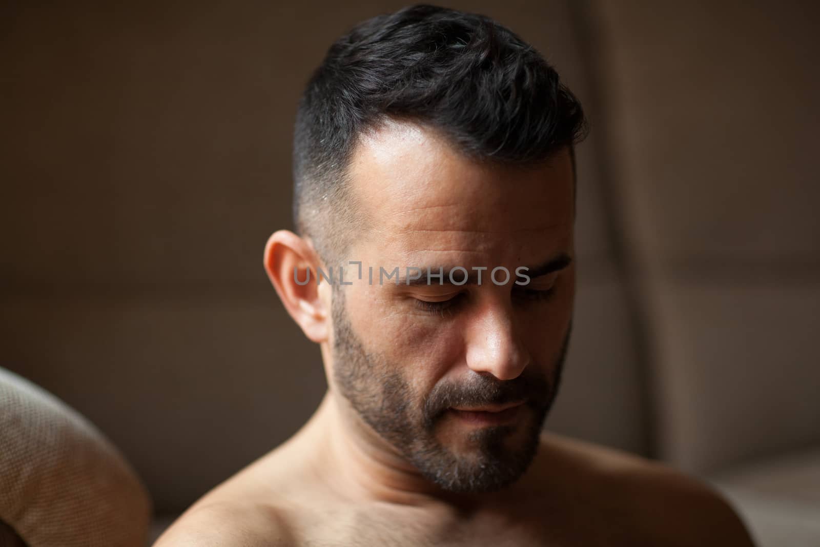 Dark-haired man looking down in soft light
