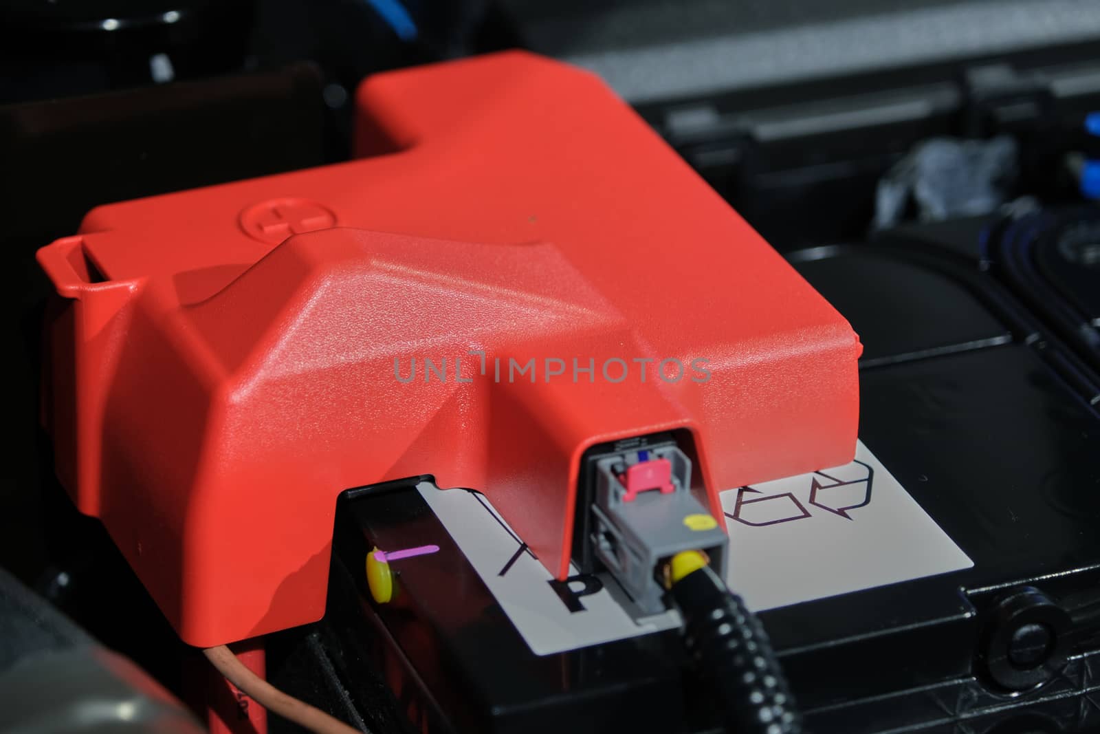 plastic cover of the positive battery cell tip with the red plus symbol, the battery is placed in the engine compartment. by peerapixs