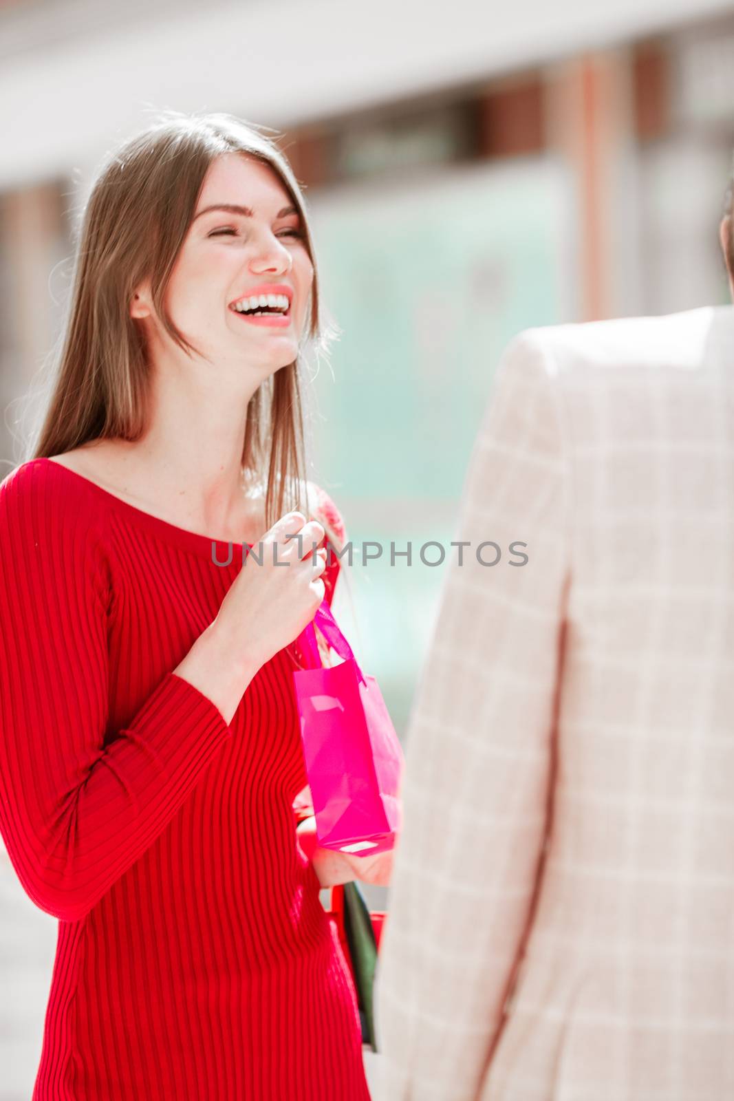 Happy laughing smiling woman in shopping mall holding pink gift bag