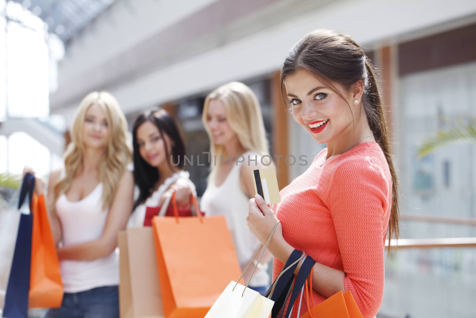Young beautiful happy women with shopping bags and credit card in mall