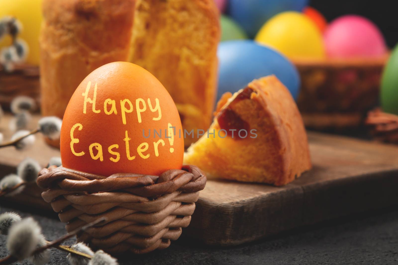 Egg with the inscription Happy Easter in a wicker stand, Easter cake on a cutting board and painted eggs on the table - traditional Easter breakfast by galsand