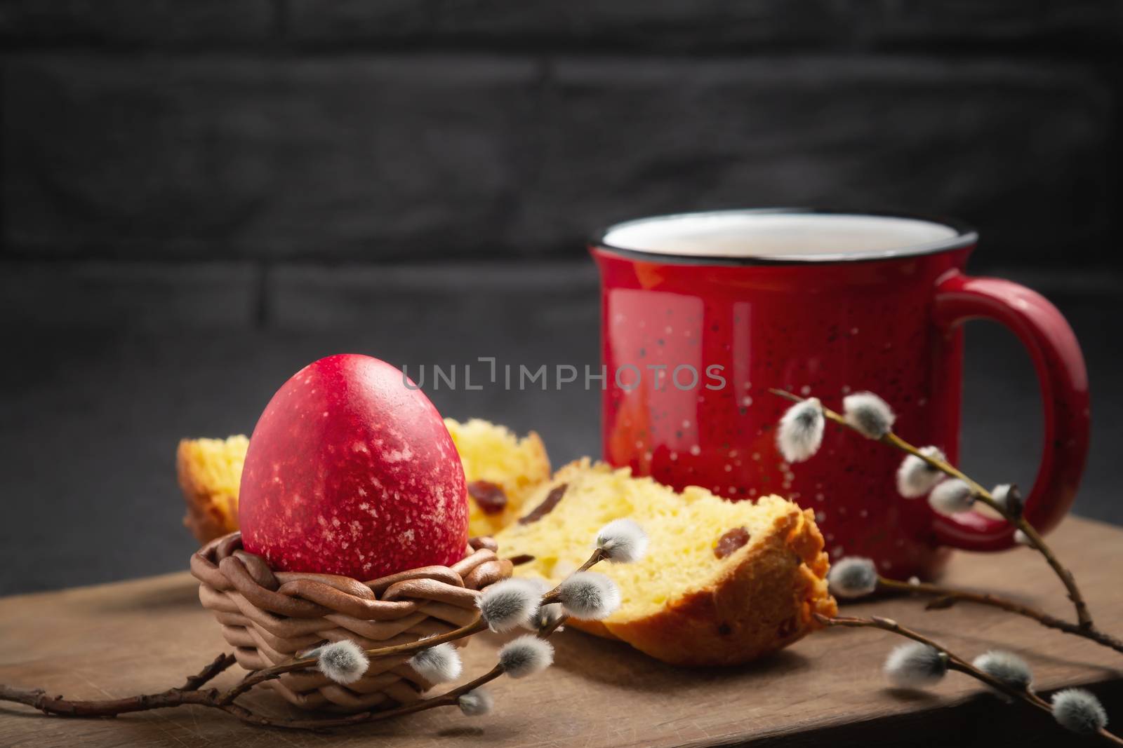 Red Easter egg, a slice of Easter cake and a cup of coffee on a cutting board on a dark table - traditional Easter breakfast.