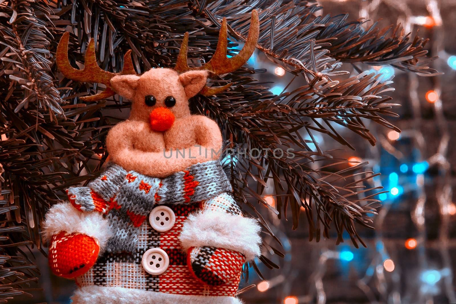 Toy deer on a Christmas tree on the background of Christmas lights.