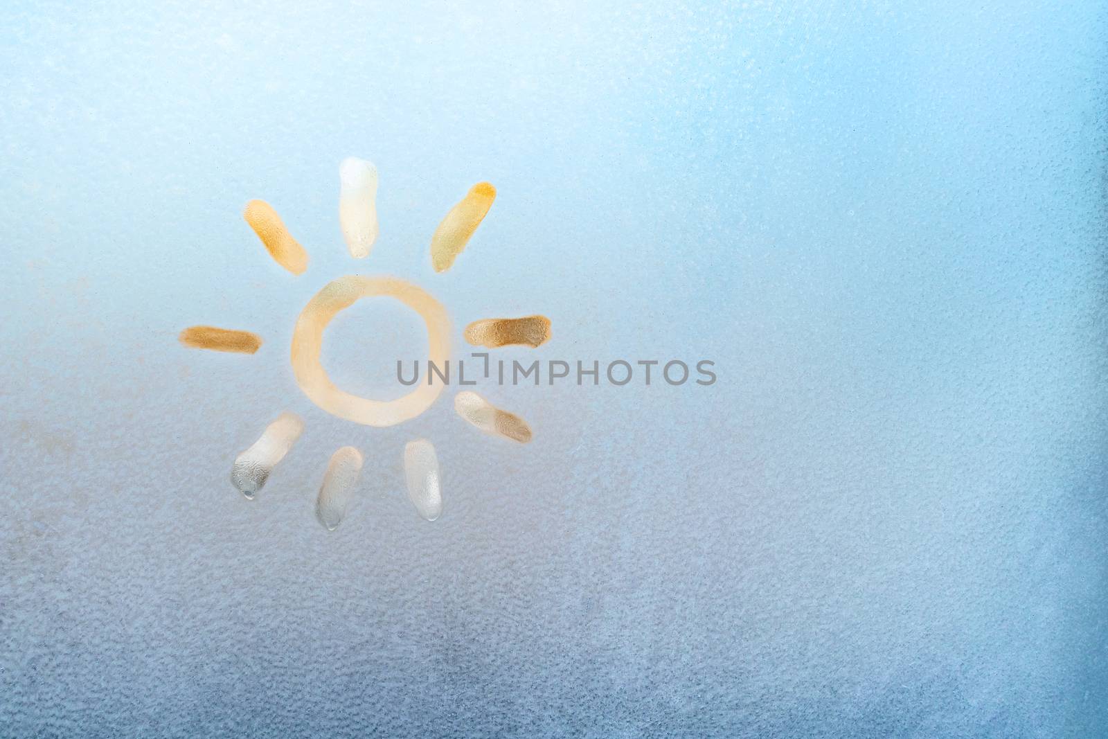 Sun painted on a frozen window, winter fun, season change and hope concept, place for text, copyspace.