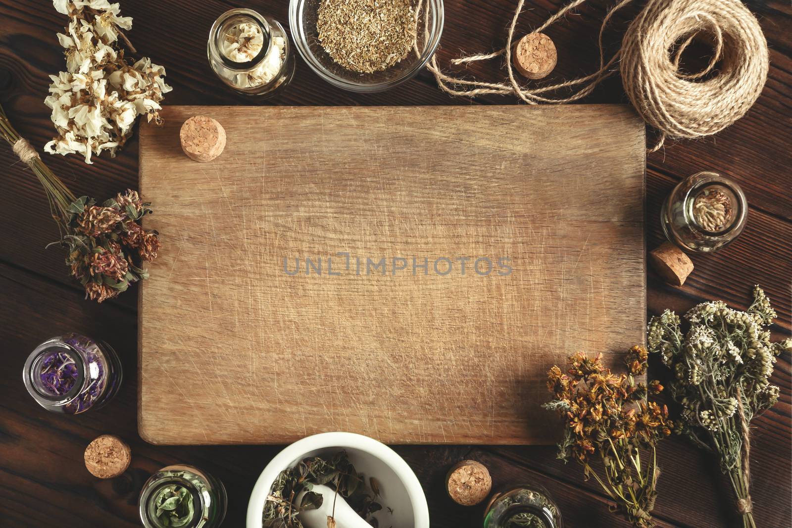Cutting wooden board with various dried medicinal herbs and devices. Homeopathy and herbal treatment concept, place for text, copy space, top view, flat lay.