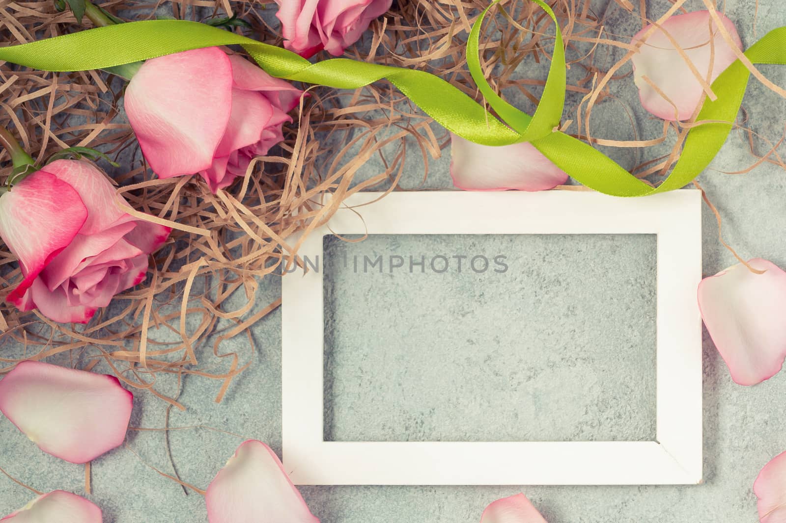 Flower arrangement - a bouquet of pink roses and an empty white wooden frame for inscription on a concrete surface, template for design or greeting card, top view, flat lay.