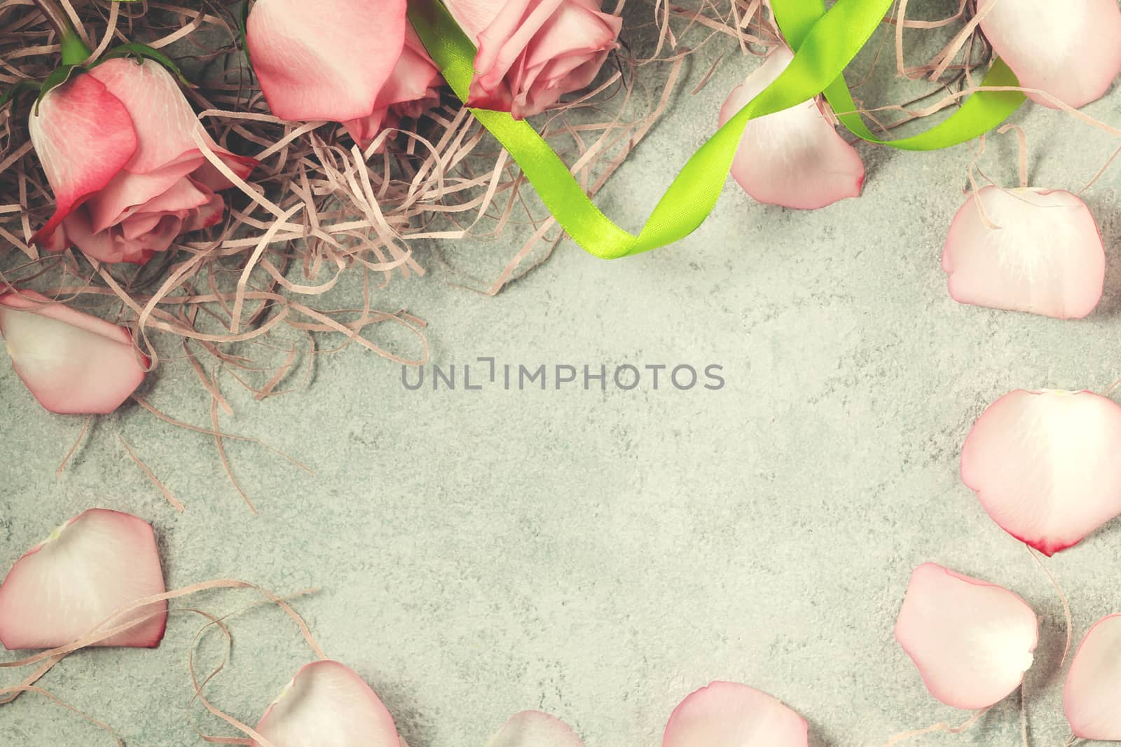 Bouquet of pink roses and petals in the form of a frame on a concrete surface, template for design or greeting card, top view, flat lay.