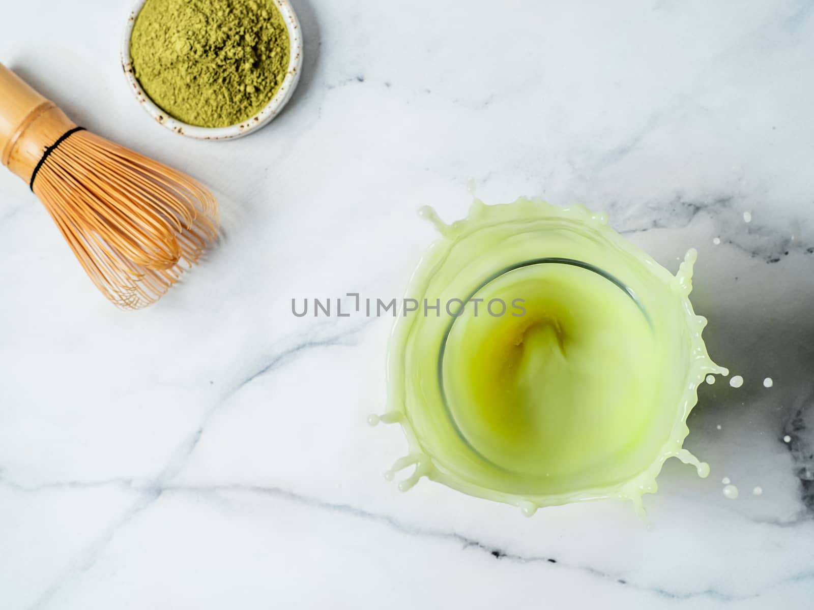 Homemade iced matcha latte with splashes over white marble background. Top view or flat lay. Copy space for text or design