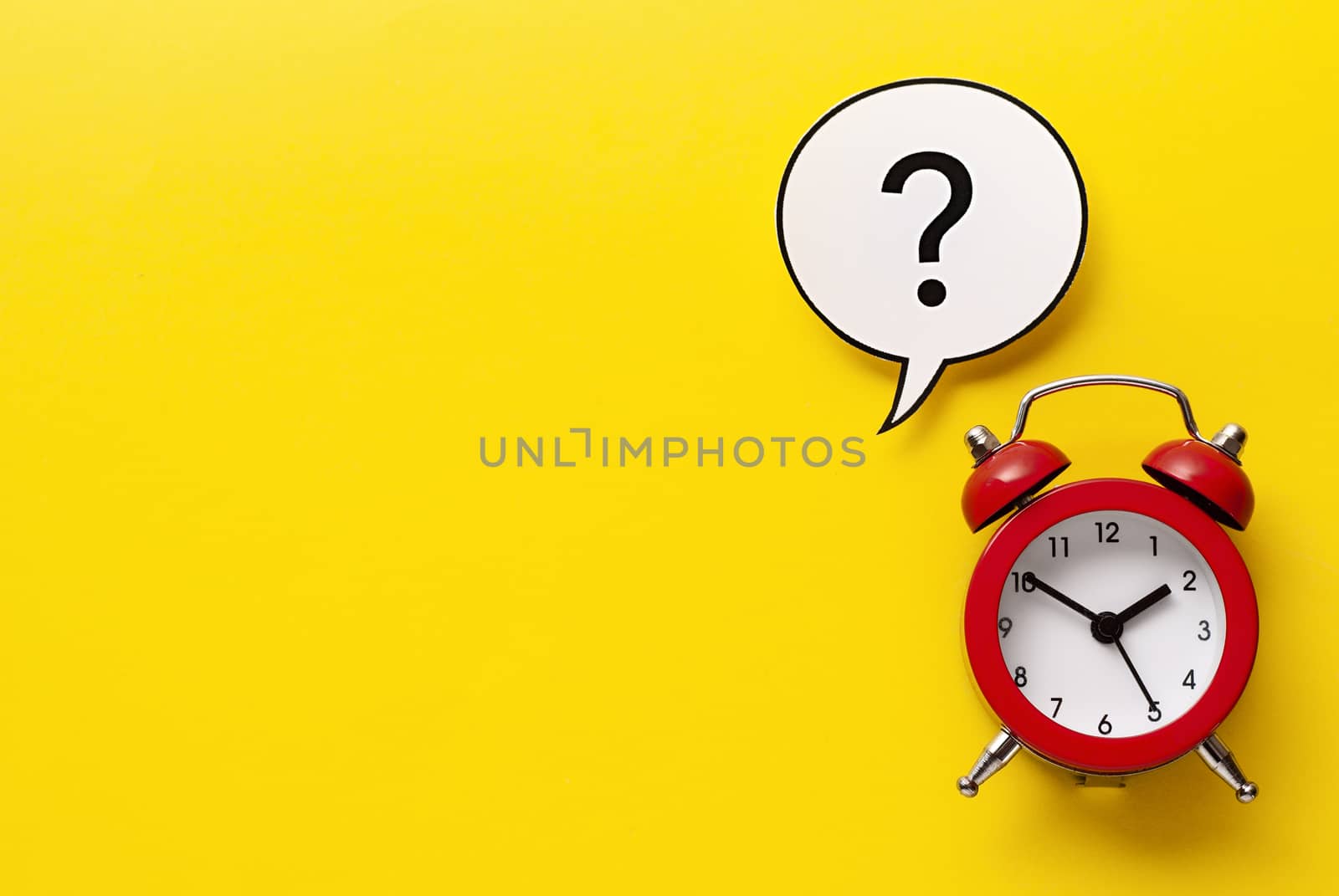 Colourful red alarm clock with question mark inside a speech bubble over a bright yellow background with copy space