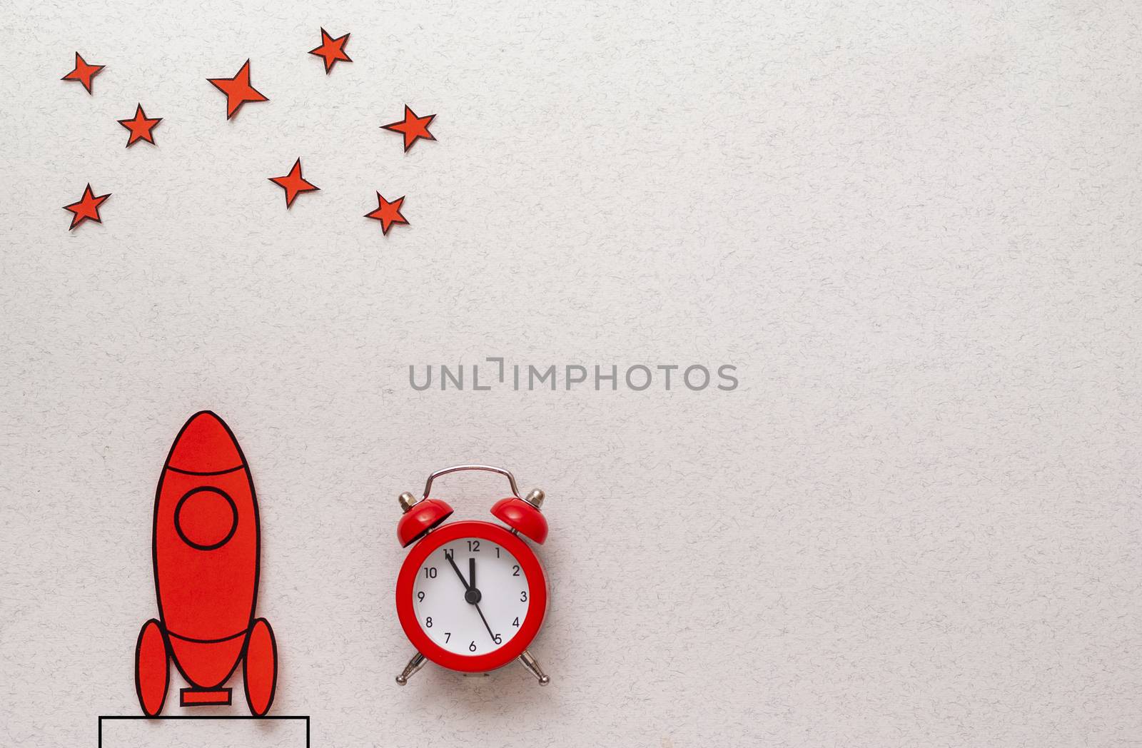 Red cartoon rocket on a launch pad aiming for the stars alongside an alarm clock counting down to takeoff over a white background with copy space