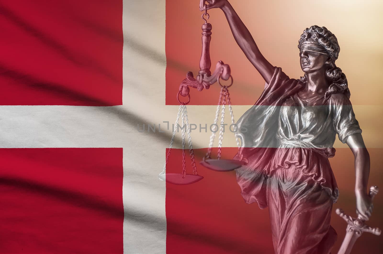 Figure of Justice holding scales and sword on a Danish flag in a conceptual image of law and order and impartiality