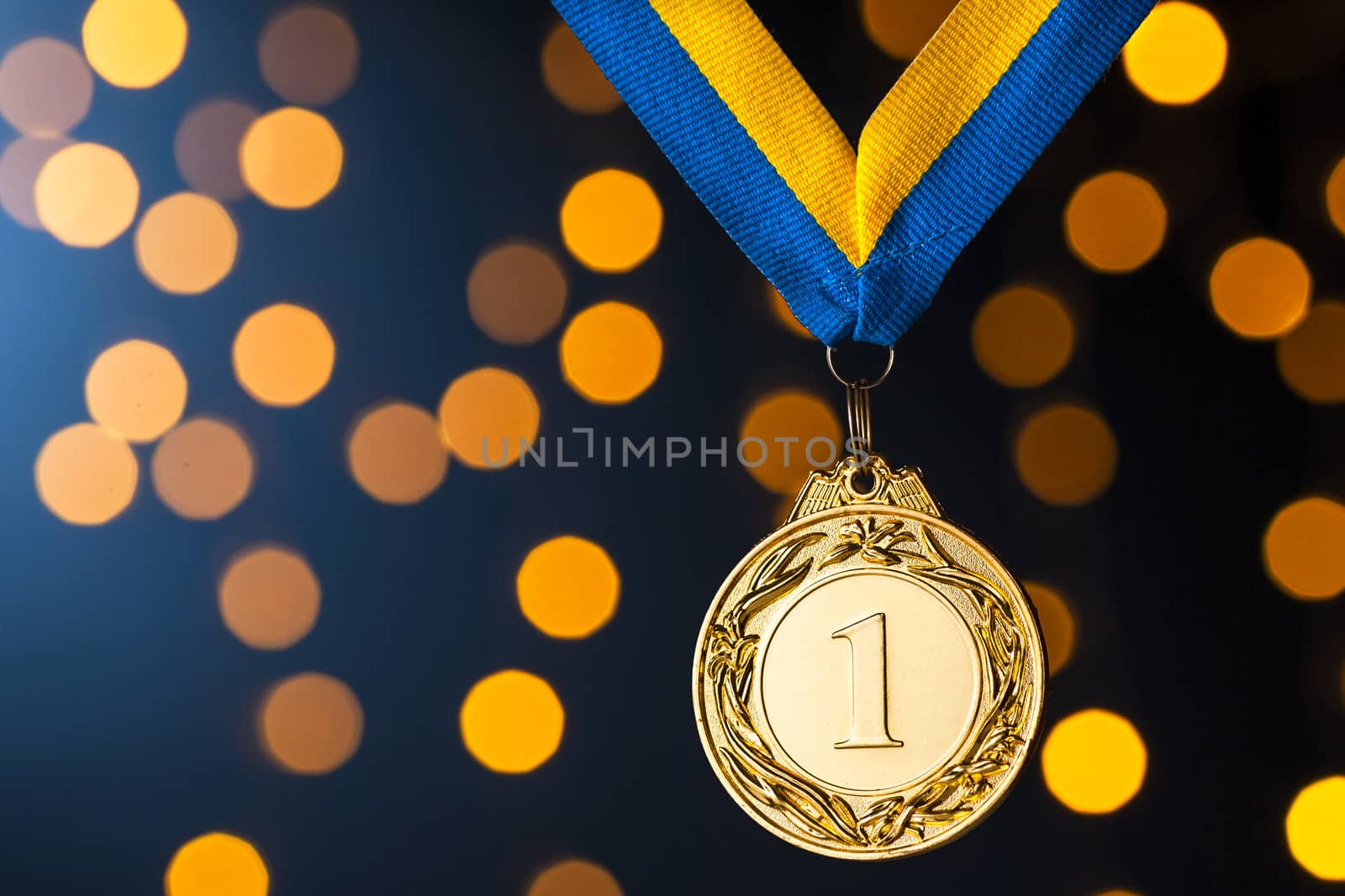 Gold champion or winners medallion on a ribbon over a blue background with festive golden bokeh of party lights to celebrate the win