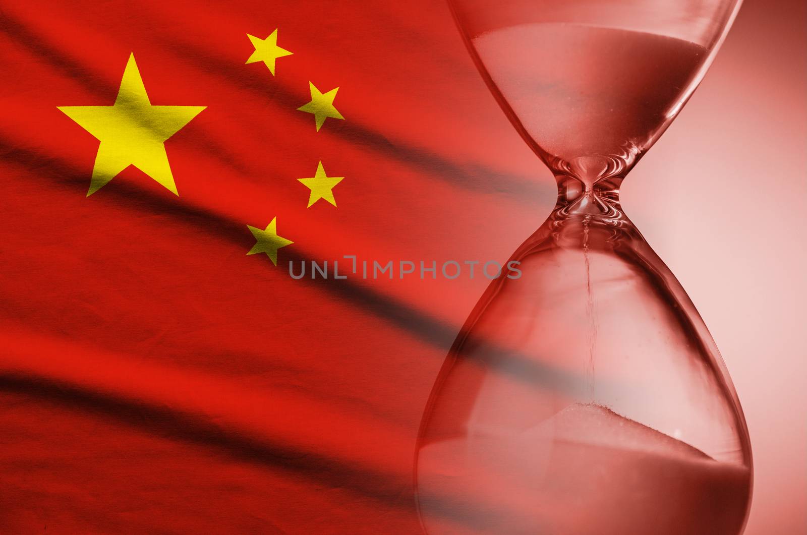 Sand running through an hourglass on the flag of China in a conceptual image of deadlines, urgency, and countdown