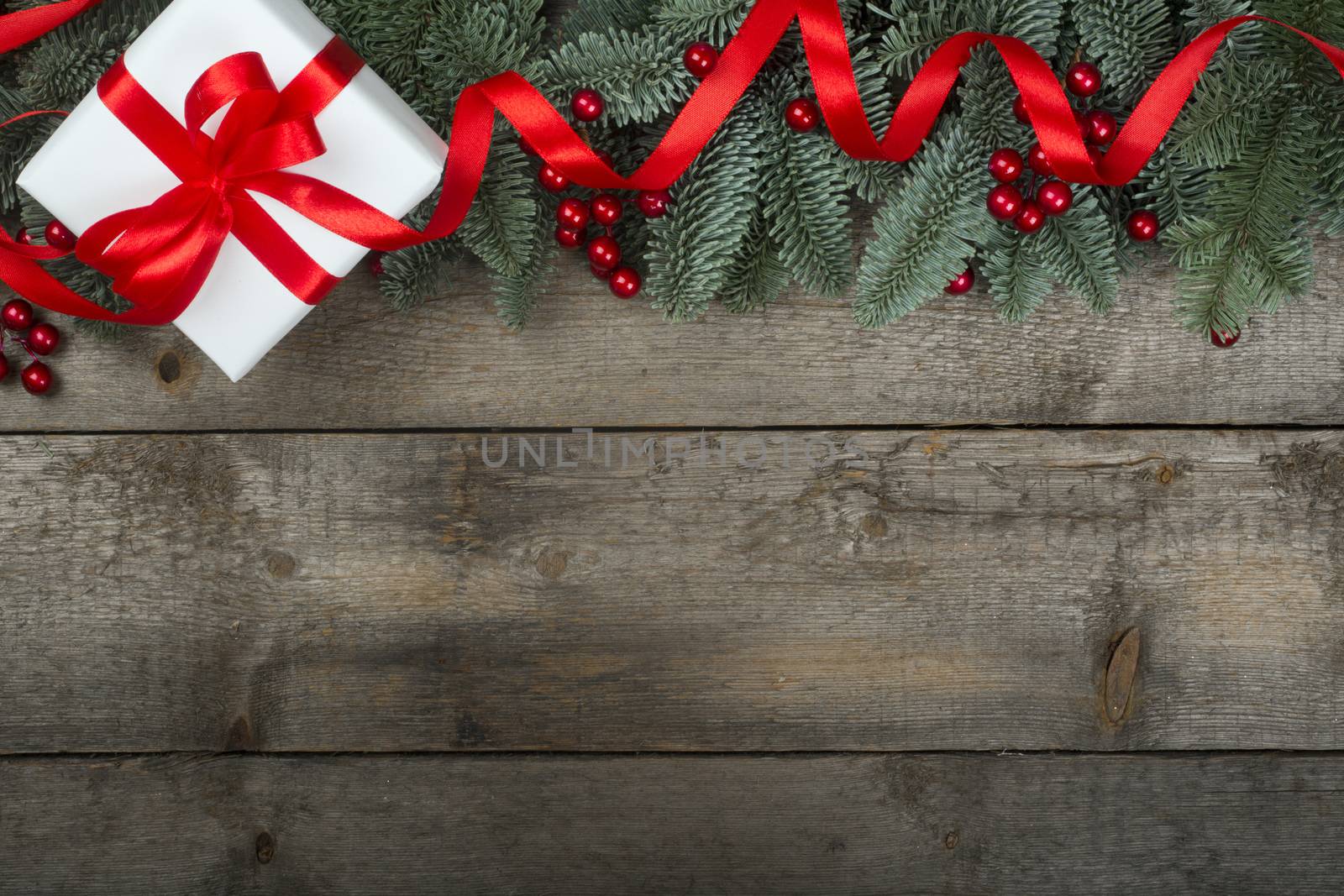 Christmas noble fir tree twigs and gift with red ribbon on wooden background with copy space for text