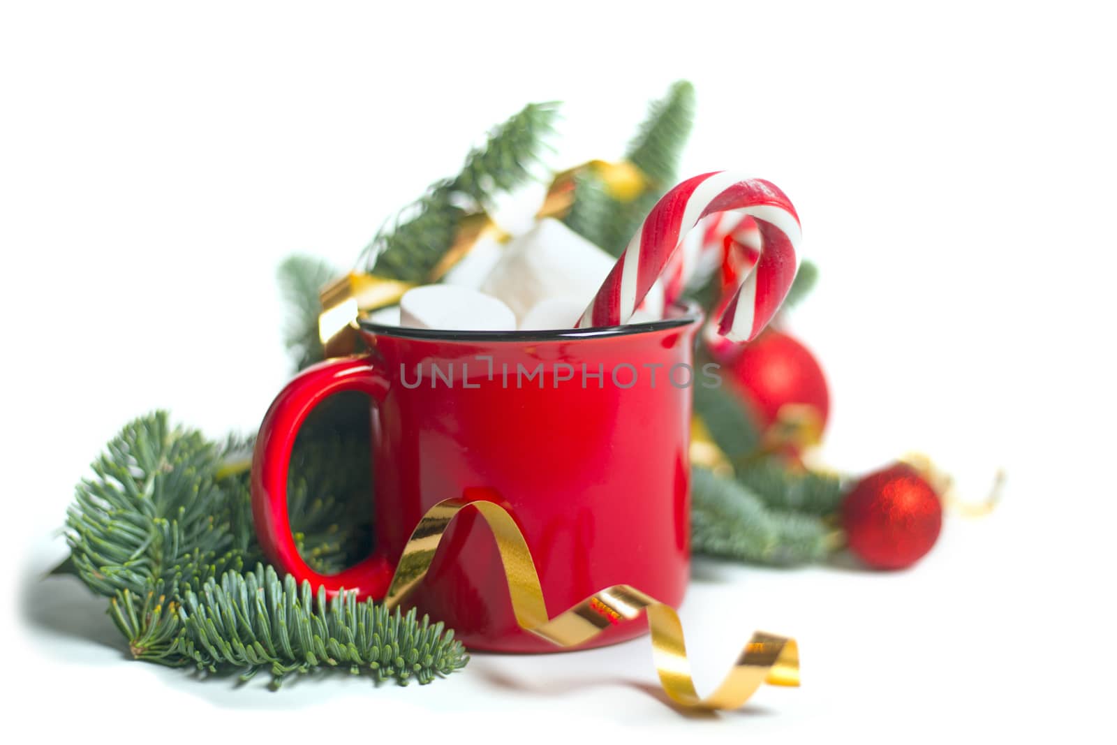 Cocoa in red mug with marshmallows and candy cane and fir tree branches and red and golden baubles and stars isolated on white background