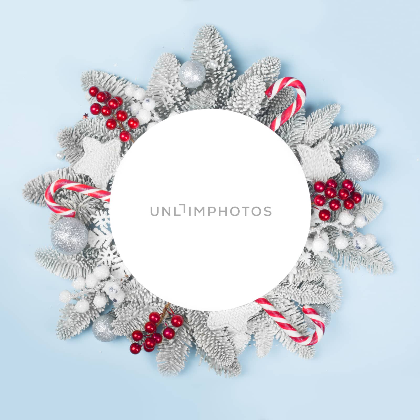 Frosted fir tree twigs and Christmas decorative bauble balls on blue background with white circle card with copy space for text template flat lay top view design