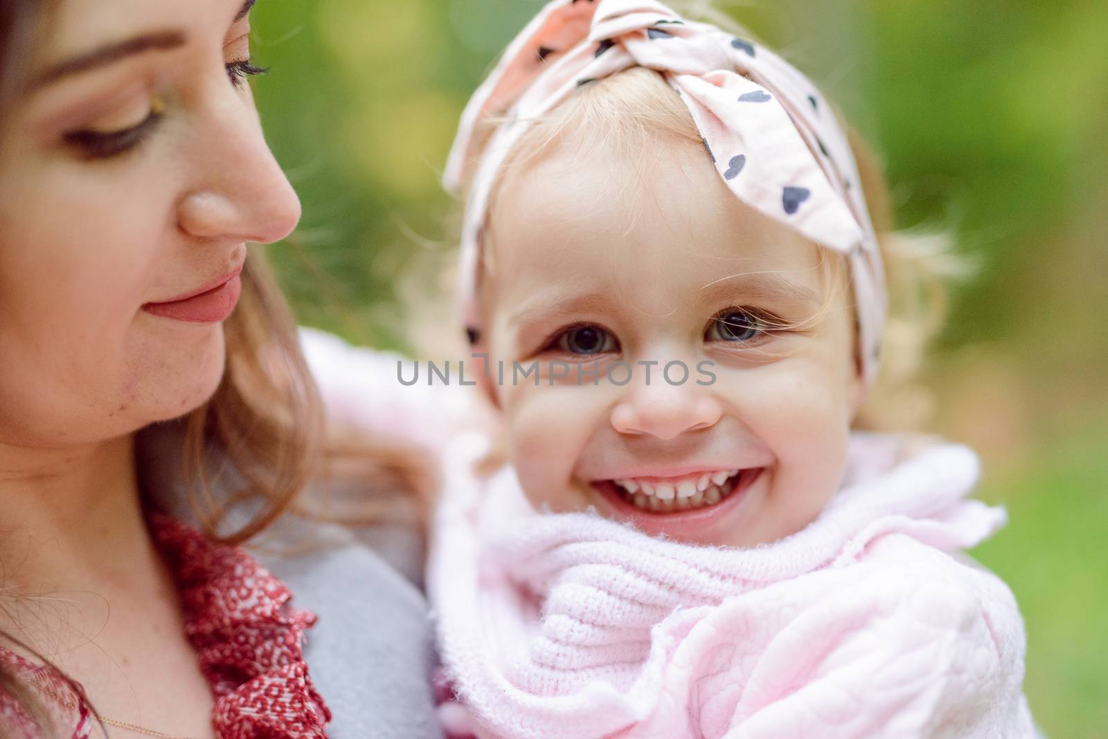 Mother holds daughter in her arms in the park on a sunny day. Autumn day