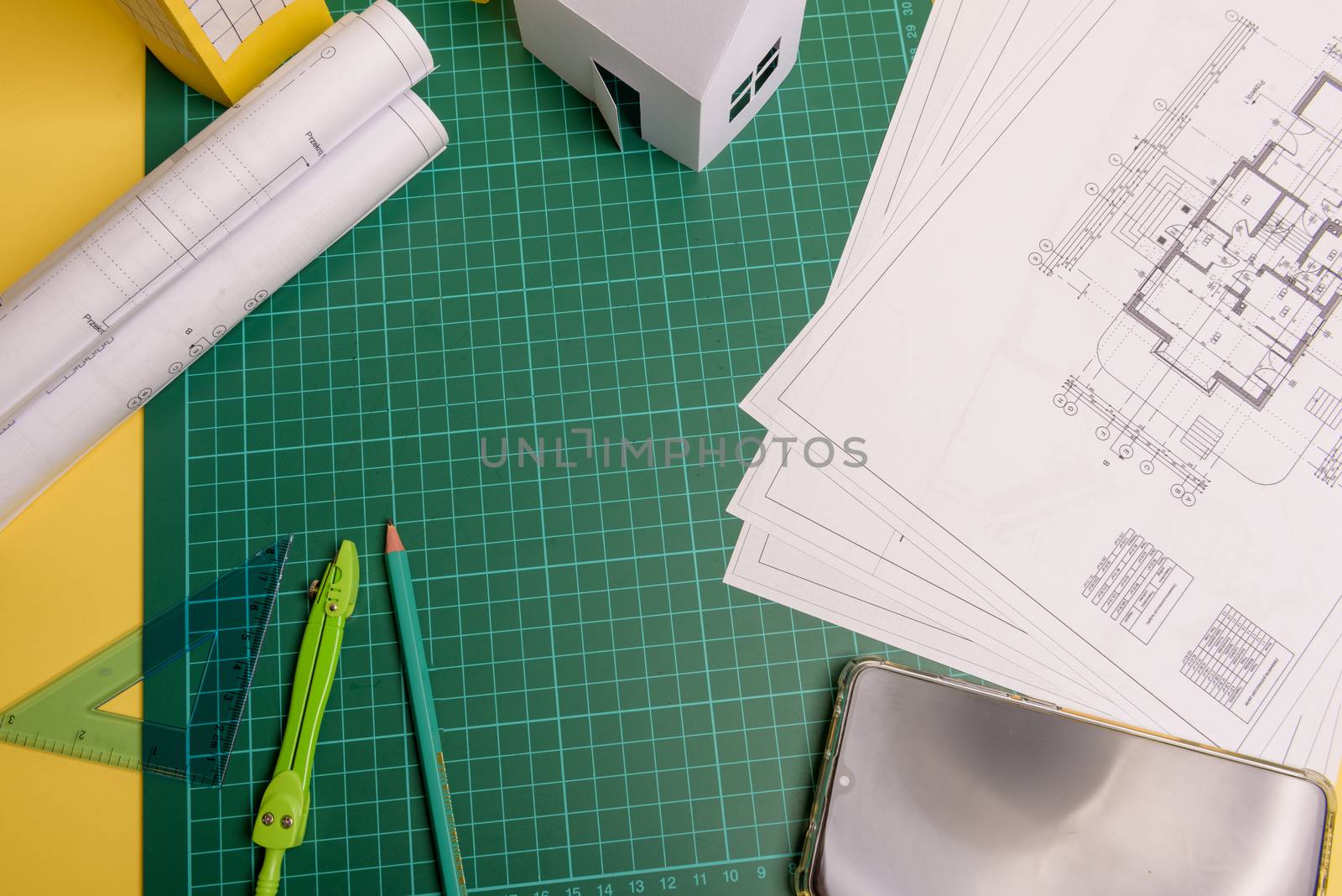 White family paper house, house projects plan and blueprints in the background. Minimalistic and simple concept, style. Horizontal orientation. View from above.