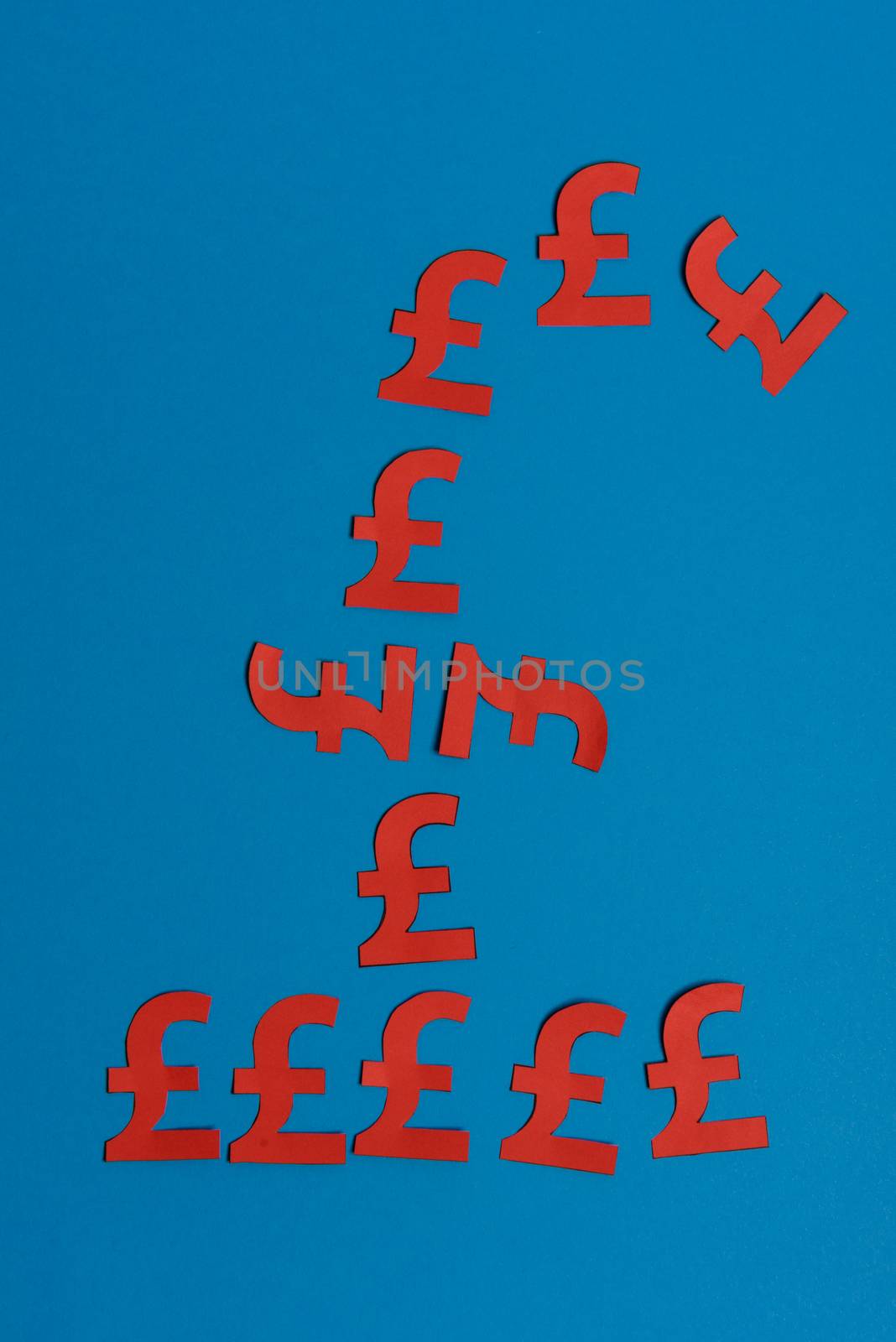Paper yellow symbols of british pound currency on blue background. View from above with copy space