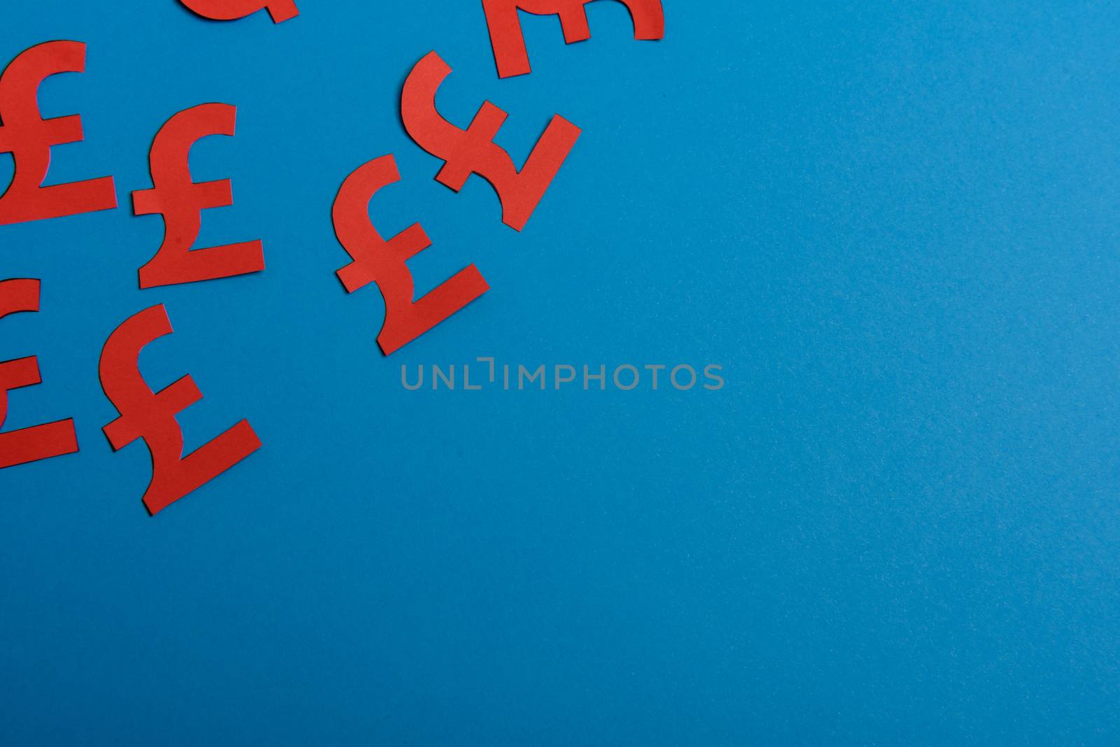 Paper yellow symbols of british pound currency on blue background. View from above with copy space