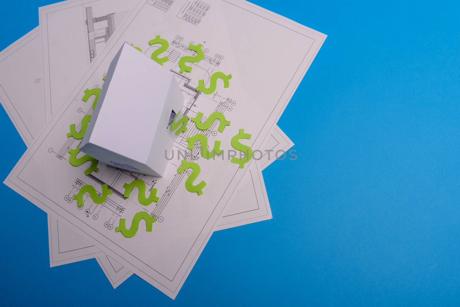 Paper skyscrapers , us dollar money, house projects plan and blueprints on blue background paper. Minimalistic and simple concept, style. Horizontal orientation. View from above. Copy space.