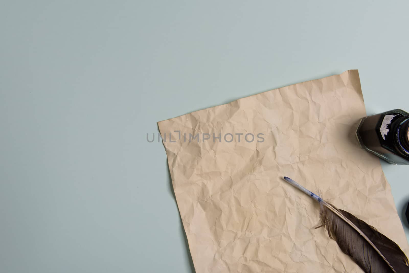 Raven feather, inkwell and old yellowed paper on red background. Copy space. Old letter.