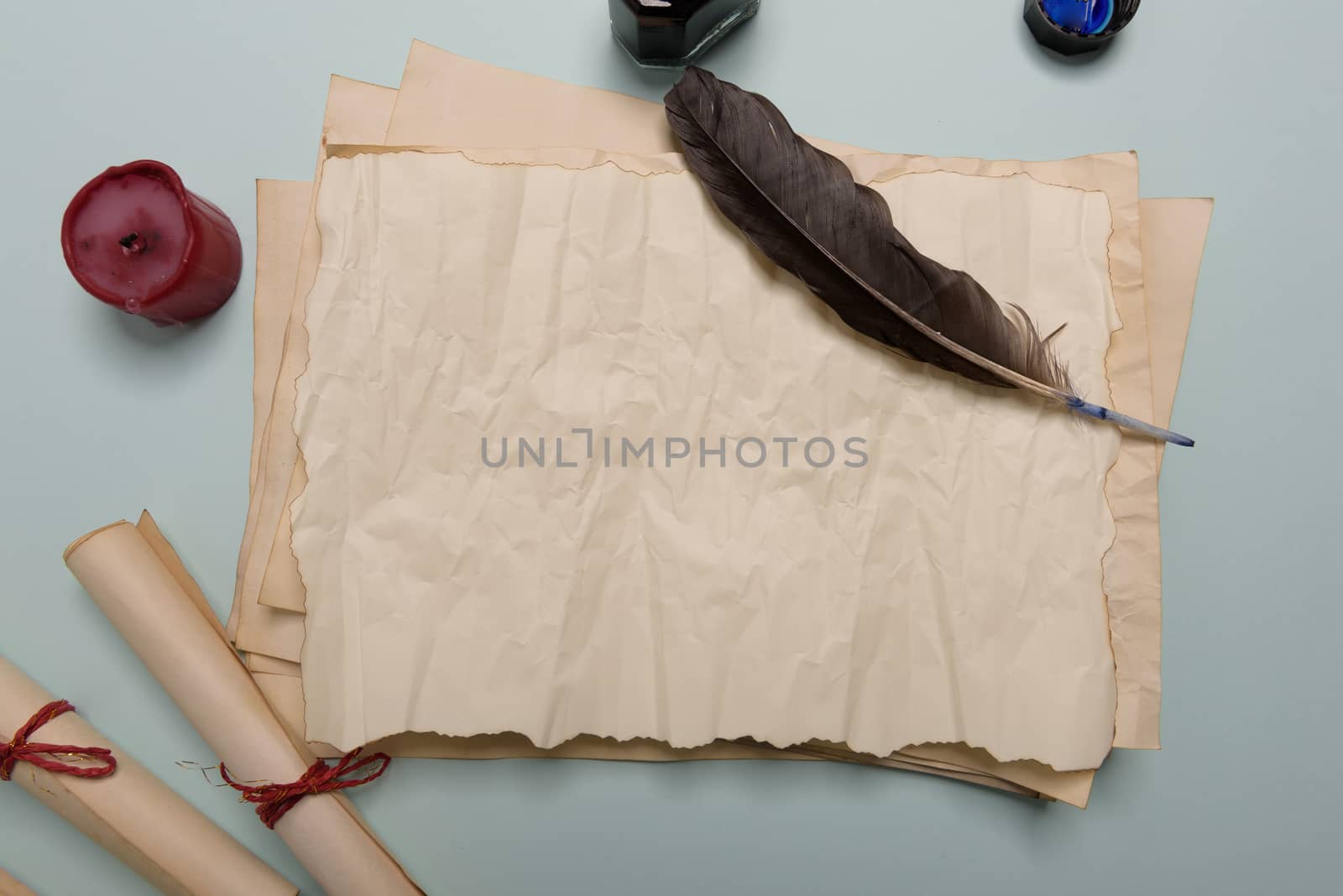 Raven feather, inkwell and old yellowed paper on red background. Copy space. Old letter.