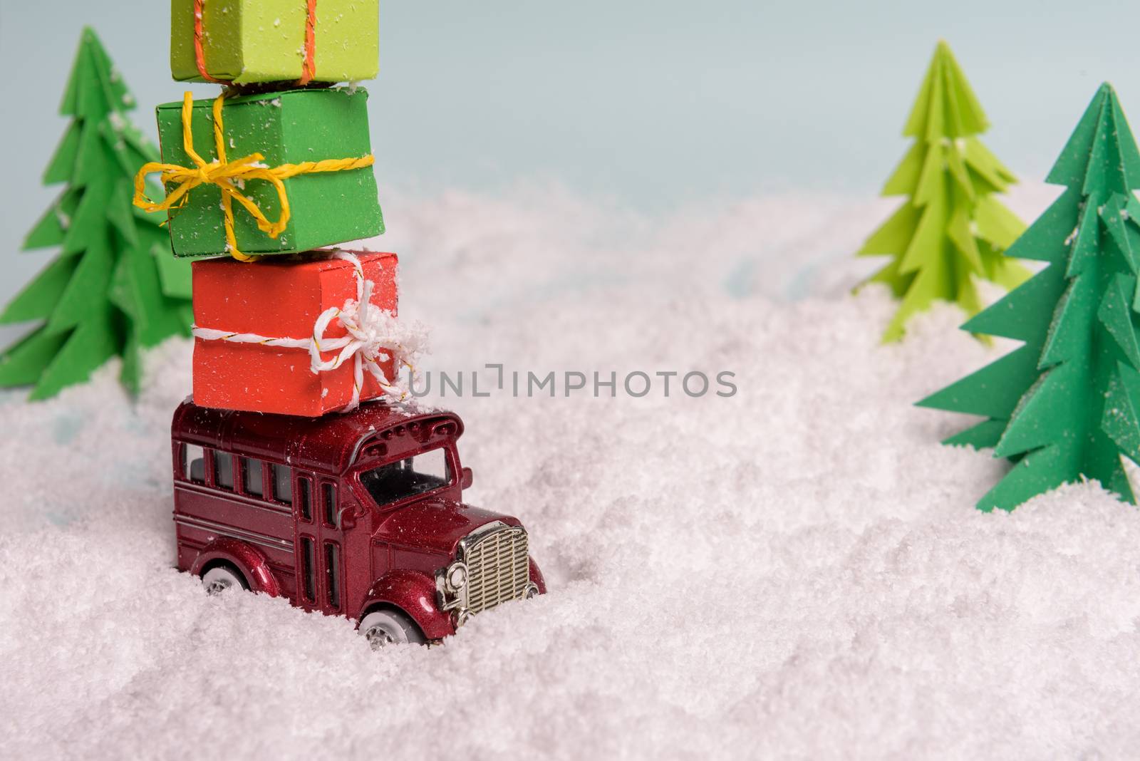 a toy car carries presents under the Christmas tree at snow. view from above. copy space
