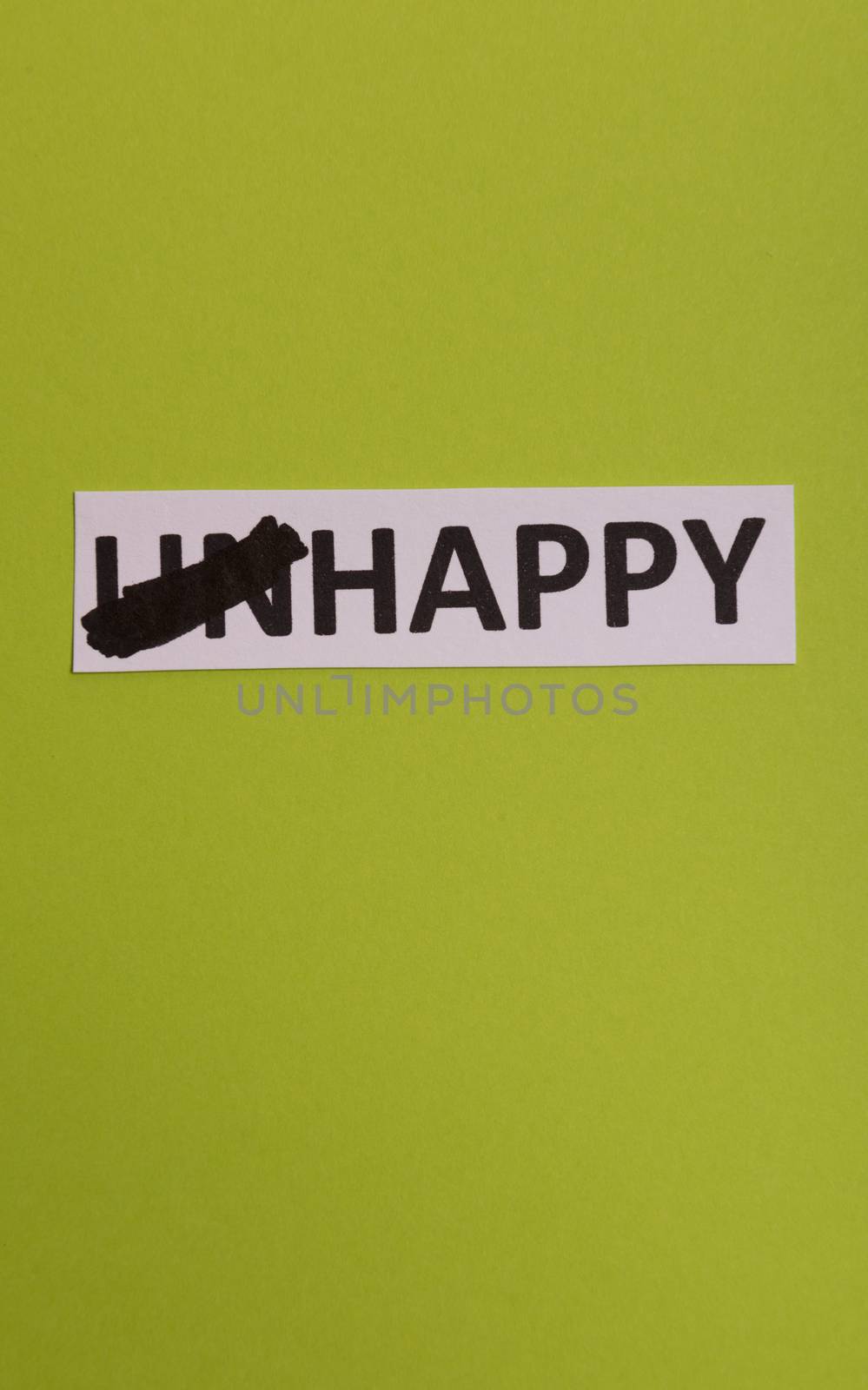 card with text unhappy, cutting word 'un' so it written 'happy'. Copy space. Lime background. Studio shoot.