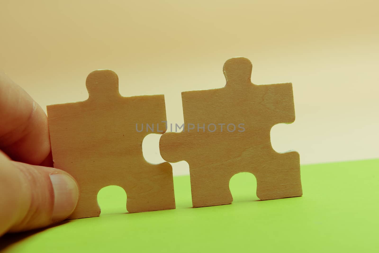 Man hand assembling puzzles on lime background.