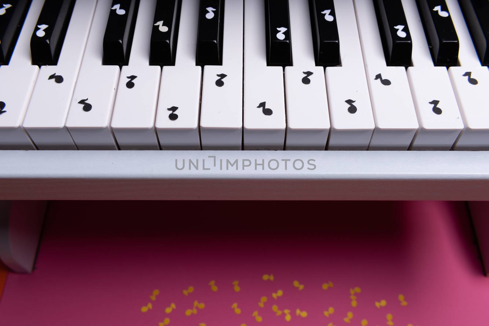 white toy piano with paper notes. music piano concept. view from above. White, black and yellow music notes.