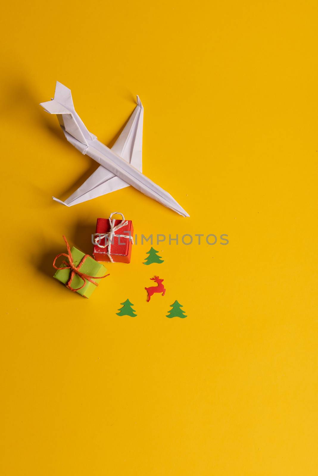 Group of paper plane in one direction and with one individual pointing in the different way on yellow background. Christmas ttrip. Presents and gifts
